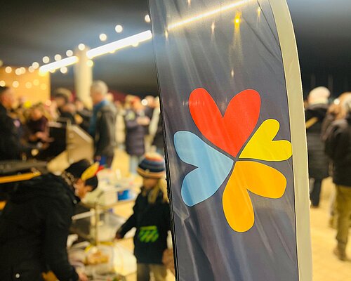 Logo Förderverein auf Flagge farbig vier Herzen rot, blau, gelb, orange